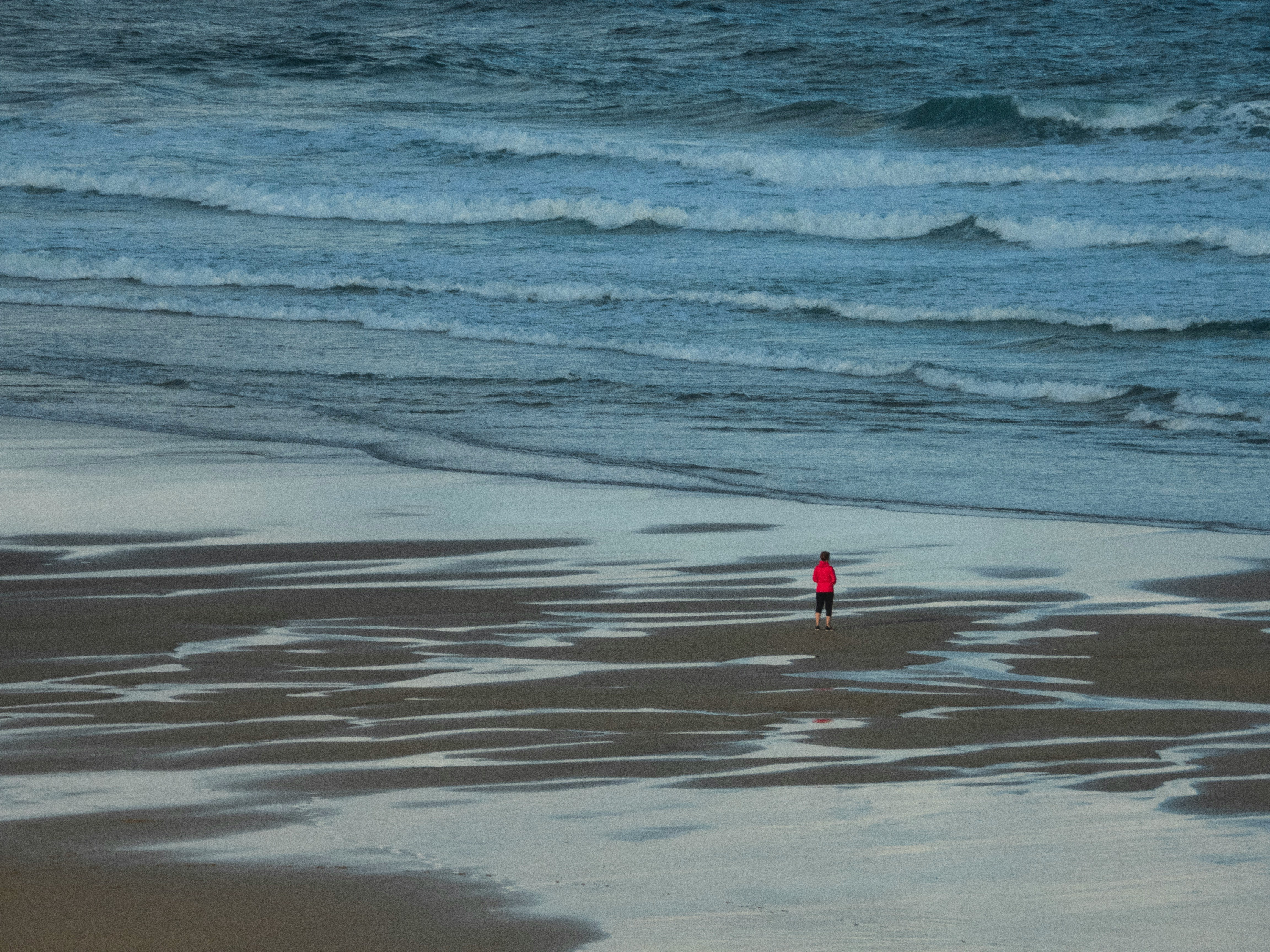person wearing red shirt standing on seashore